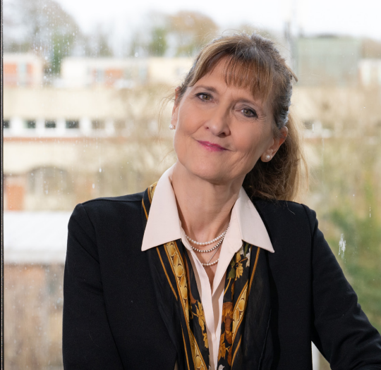 A photograph of Gabriella Cagliesi. Smiling in front of a window.