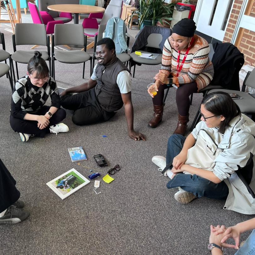 A photo of students from the Intercultural Reflection Series sitting in a circle, smiling and talking to one another. 