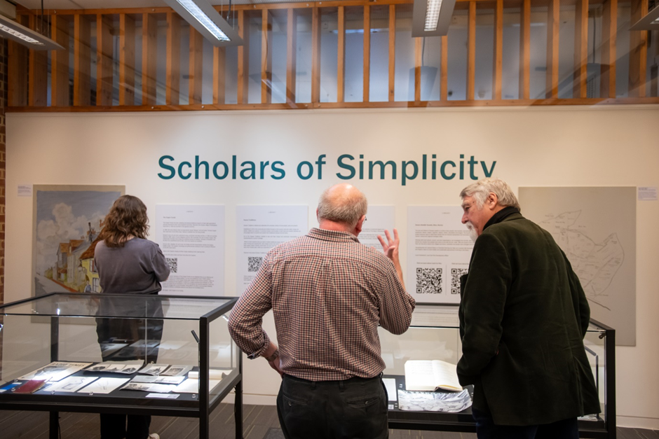 Three people looking at the Scholars of Simplicity display