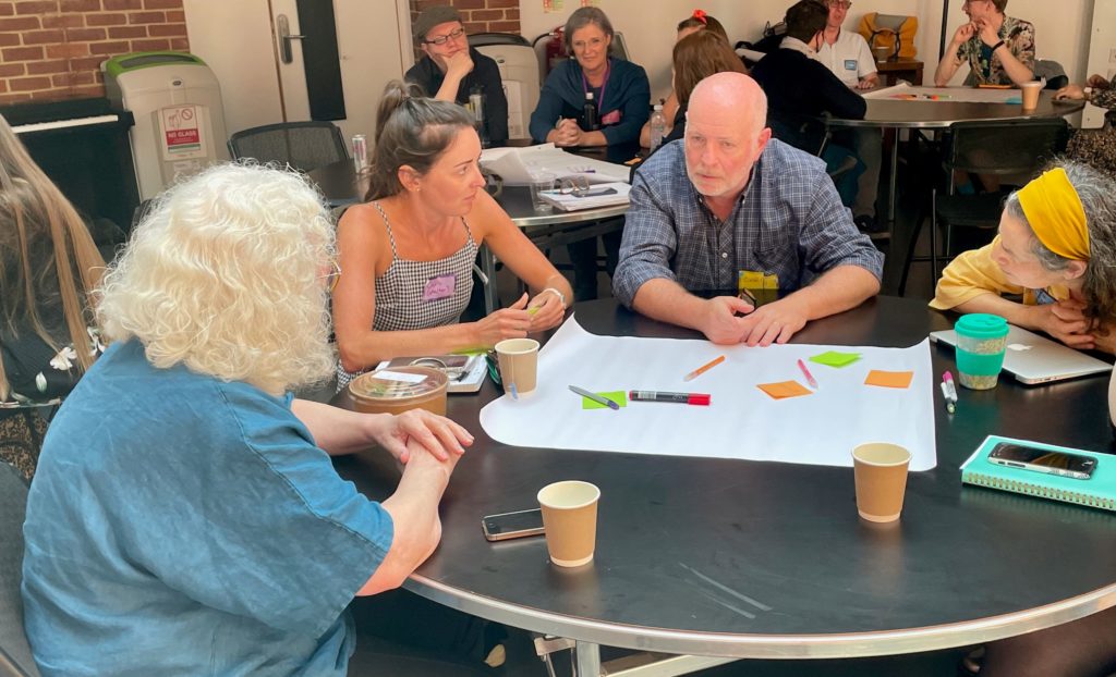 four people sitting at a table, having a discussion at a workshop